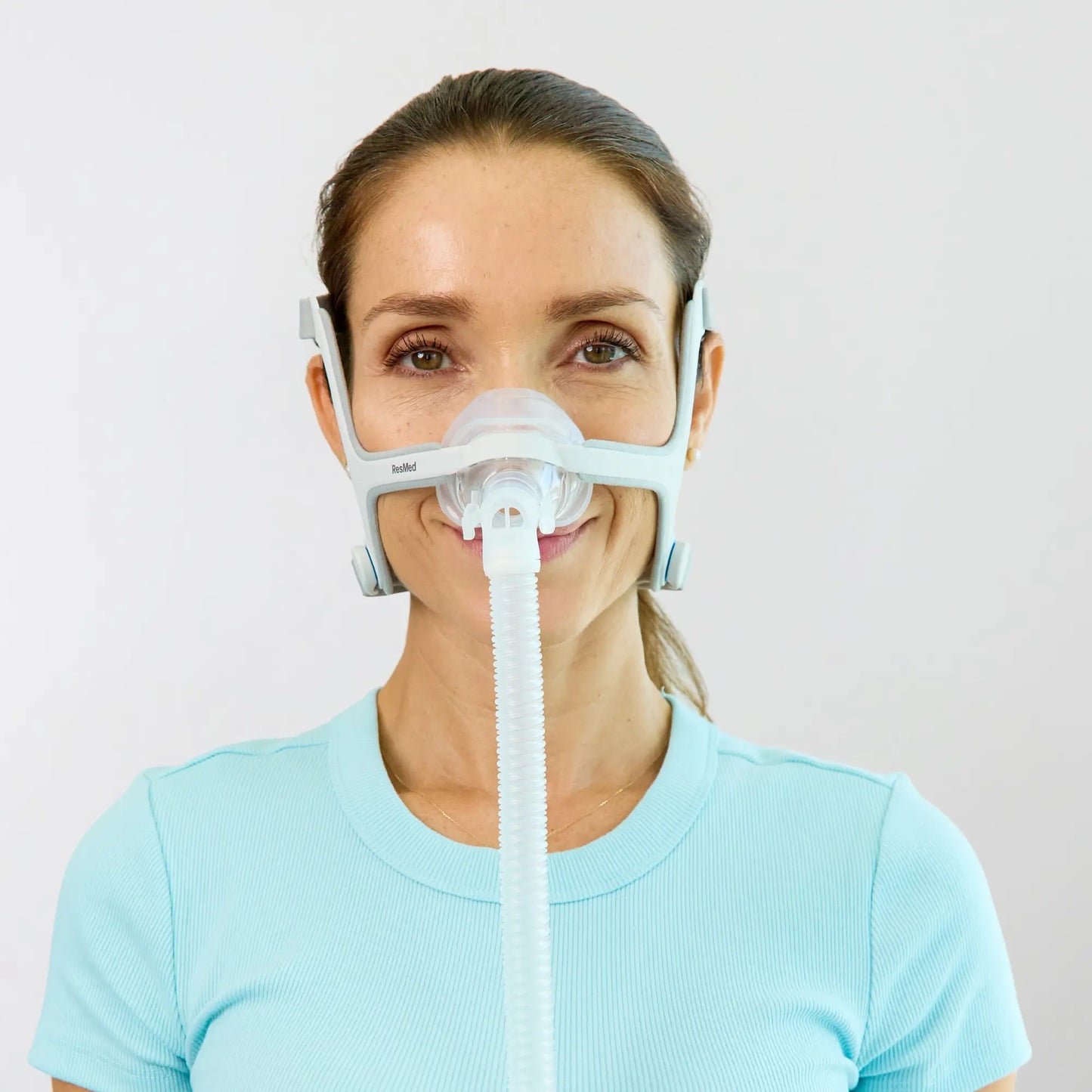 https://cdn.shopify.com/s/files/1/0318/9771/4819/files/woman-using-the-resmed-airfit-n20-nasal-cpap-mask-with-headgear-front-view.webp?v=1745263236